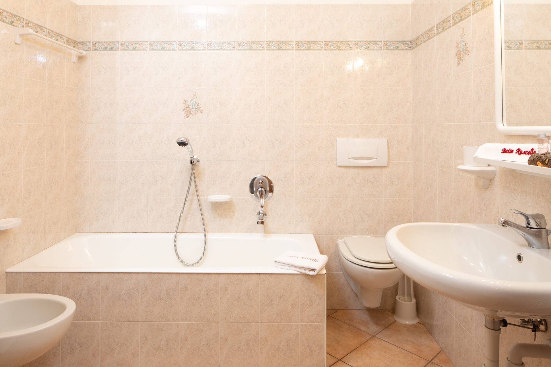 A bathroom with tub and one with shower in the Rosa Apartment of Baita Ruscello